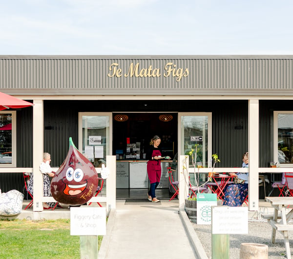 Entrance to Te Mata Figs Cafe and Shop with waiter carrying coffees out to diners sitting at outdoor tables