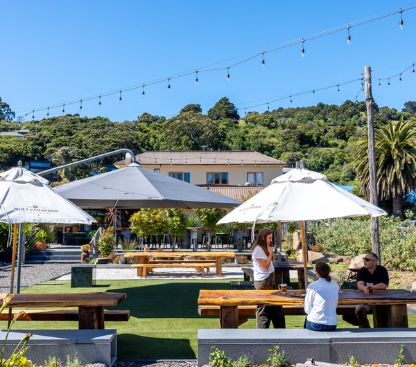 People sitting together under umbrella at outdoor table at The Grand Hotel in Akaroa