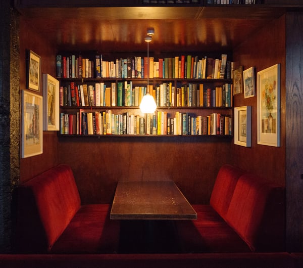 A booth beneath a shelves of books at The Library bar Wellington.
