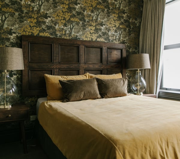 A bed dressed green and yellow in pillows and duvet cover inside The Old Confectionery Oamaru.
