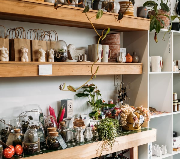 Flowers and candles on display on white shelves inside The Wilderness.