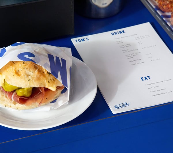 A sandwich and menu sitting on a blue table.