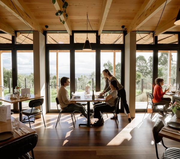 Interior of Tussock Hill restaurant with customers dining against the panoramic windows that look out over the Christchurch Port Hills.
