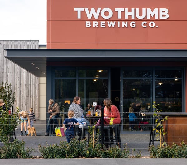 Exterior of Two Thumb Harbourside with people drinking and eating at tables