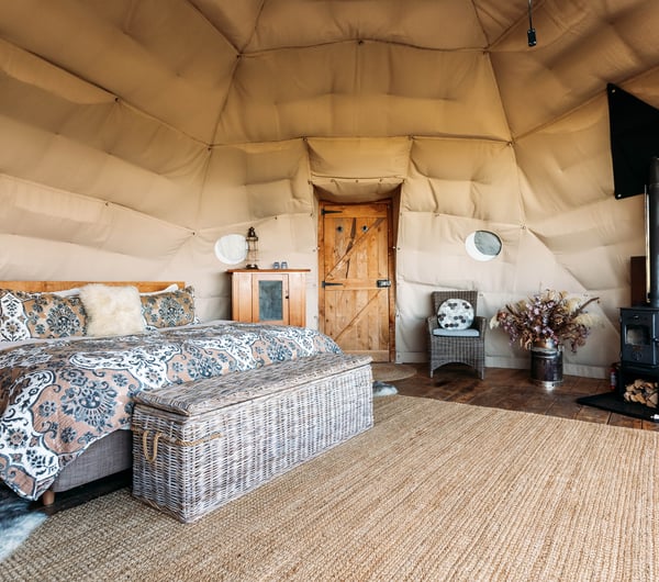 A bedroom set inside a Glamping pod with a wooden panelled floor.