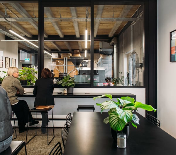 Customers sitting at high black tables inside the cafe.
