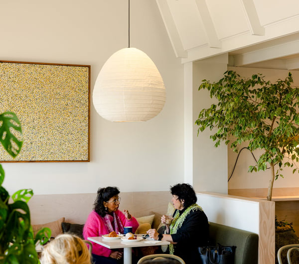 Two women talking together at a table with plates of pastries and baked goods