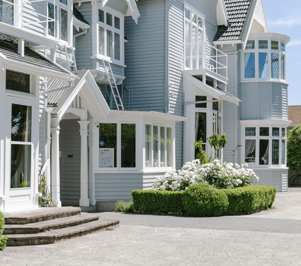 The exterior of Christchurch accommodation with roses and hedged in front.