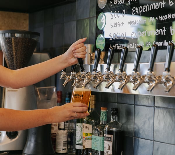 A staff member pulling a pint of craft beer behind the counter at B.Effect in Wanaka.