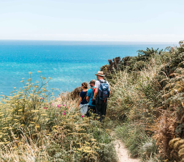 A group of people are walking on a track with the ocean in the background.
