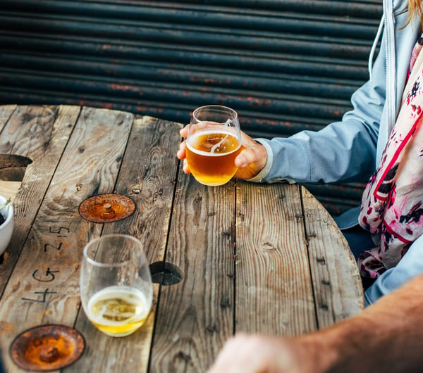A hand holding a glass of beer inside Bootleg Brewery.