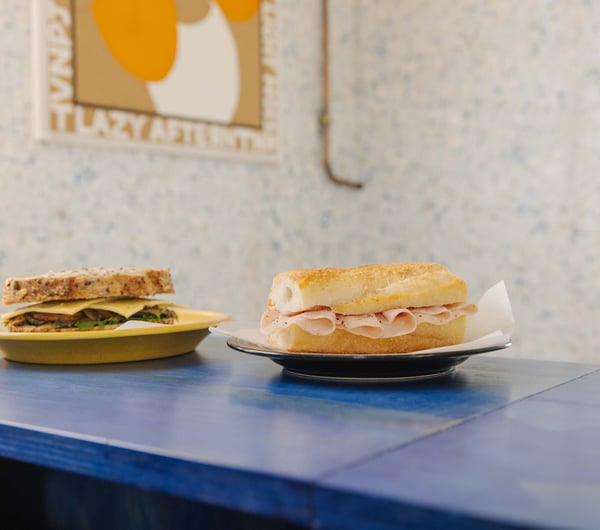 Two simple sandwiches placed next to each other on blue table at Odds in Christchurch