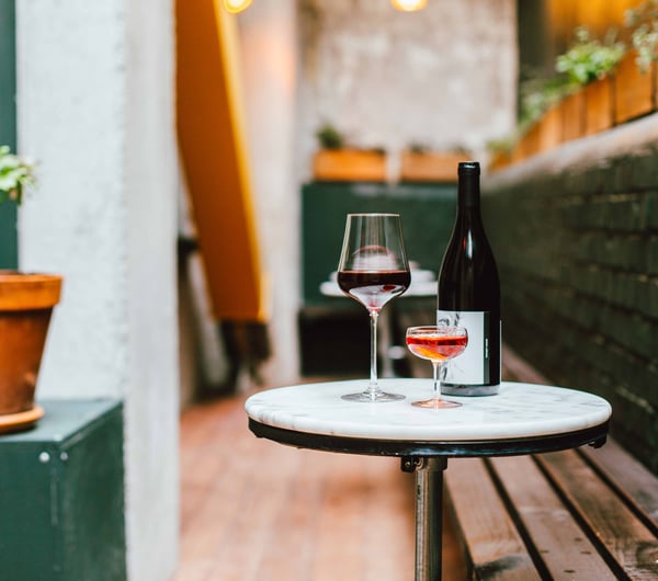 Glasses and a bottle of wine sitting on a table in the outdoor seating area of Puffin Wine Bar in Wellington.