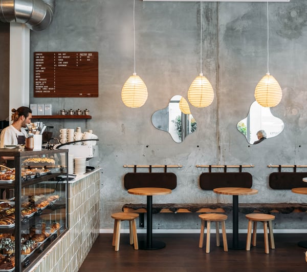 Barista behind counter and customer sitting at table at Crumb Bakehouse.