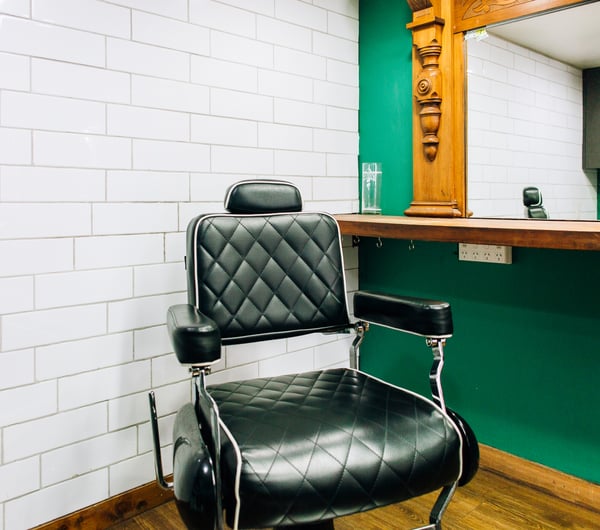 Black barber chair in front of salon mirror at Boar and Blade in Wellington