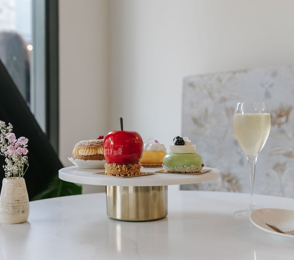 Shiny cakes on a cake stand on a white table.