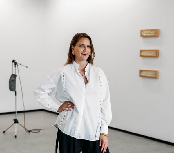A woman with her hand on her hip in front of a gallery space.