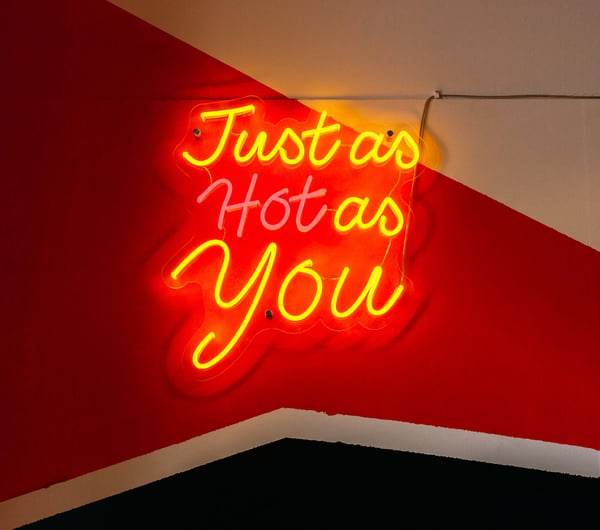 A fluorescent sign that says 'just as hot as you'.
