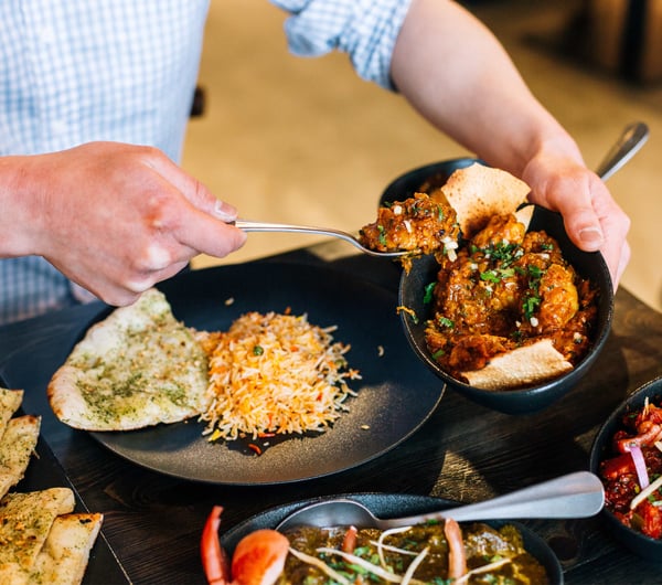 Indian food being scooped onto a plate.