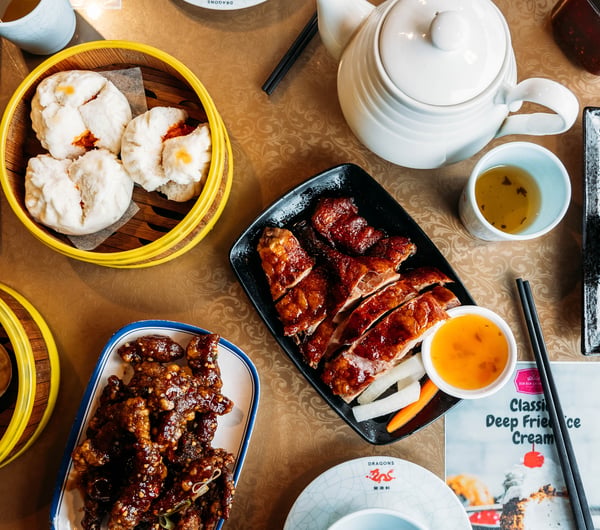 Table full of plates of Asian dishes and chopsticks.