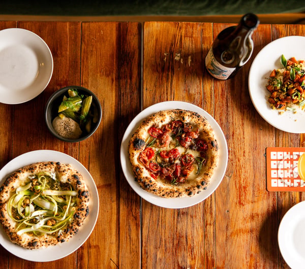 A flatlay of plates of pizza and drinks on a table.