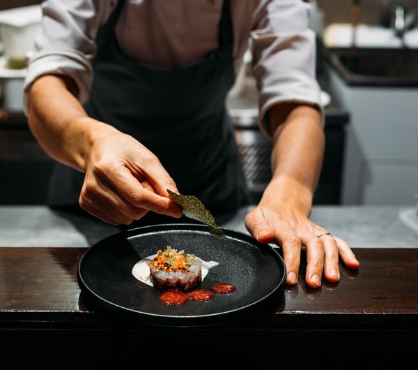 Chef finishing plating a dish on the kitchen at 50-50.