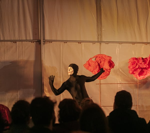 A man dressed in a black holding a red piece of fabric.