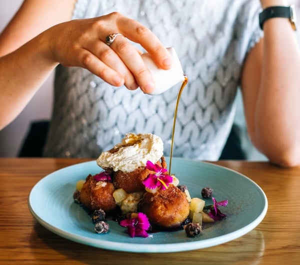Syrup being poured onto a plate of brunch.