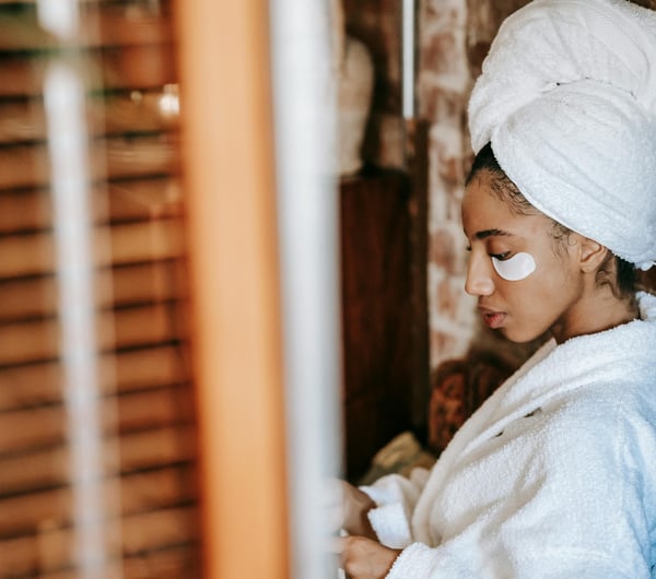 Women in spa with under-eye skincare patches wearing a dressing gown and towel wrapped around head