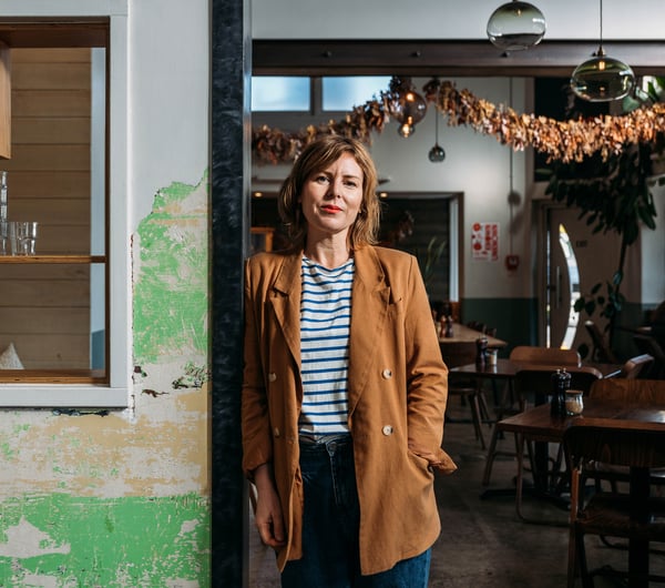 A woman in her cafe posing for the camera.