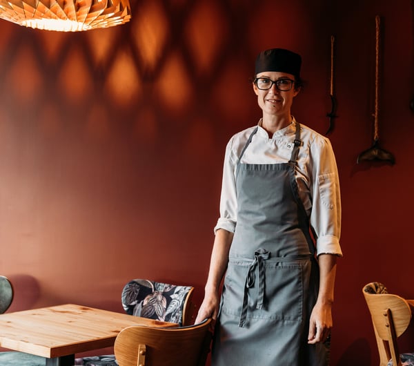 A female chef in a restaurant smiling to camera.
