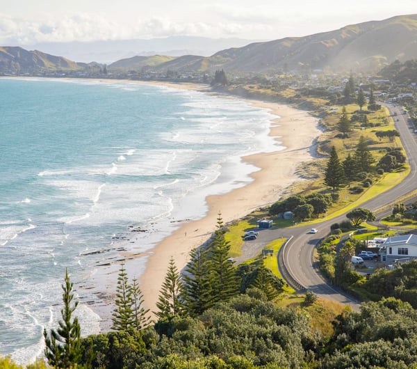 Road runs alongside the coastline, the waves on the beach meet the sand.