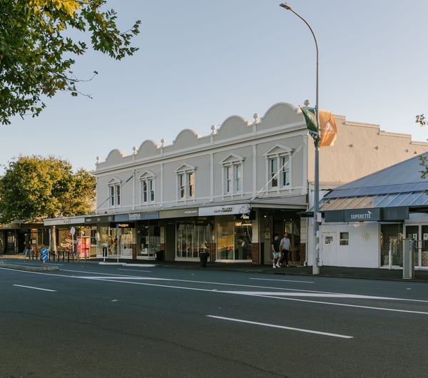 A view of old shops next to the road at dusk.