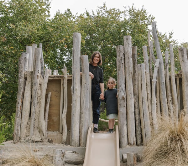 A woman and child standing amongst a log playground.