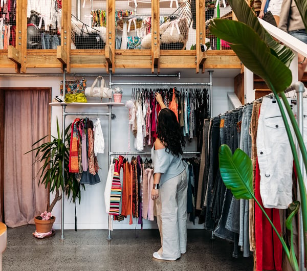 Customer browsing clothing racks in a vintage store.