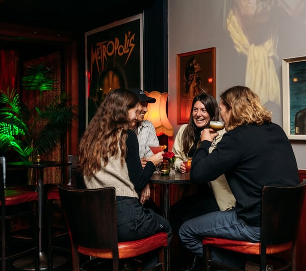 People sitting around in a dimly lit room drinking.