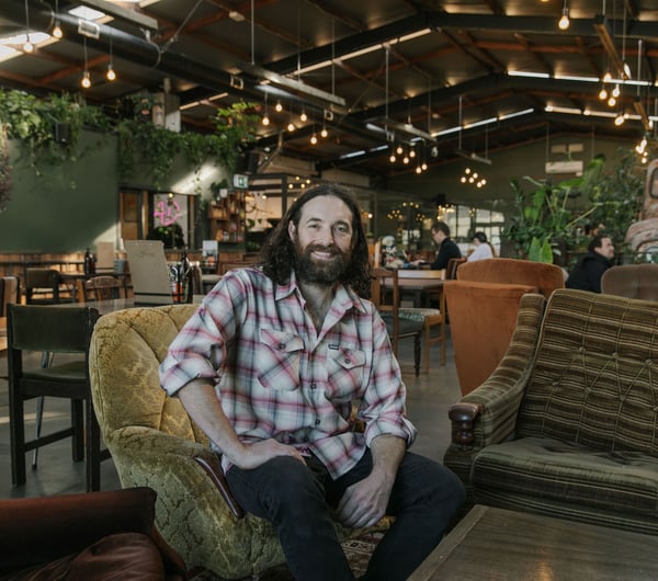 Chef Pedro Johnston sitting on couch smiling at Scoundrel in Christchurch