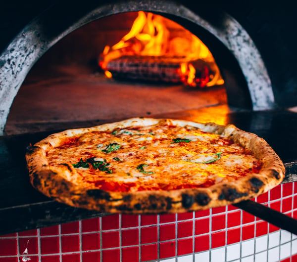 A pizza coming out of a hot oven.
