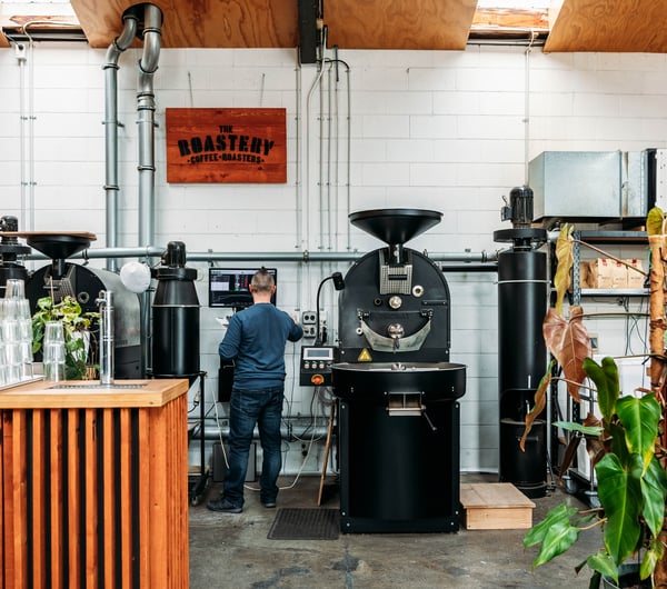 Man standing at coffee bean roaster.