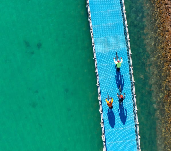 Three people biking on a bike trail over water.