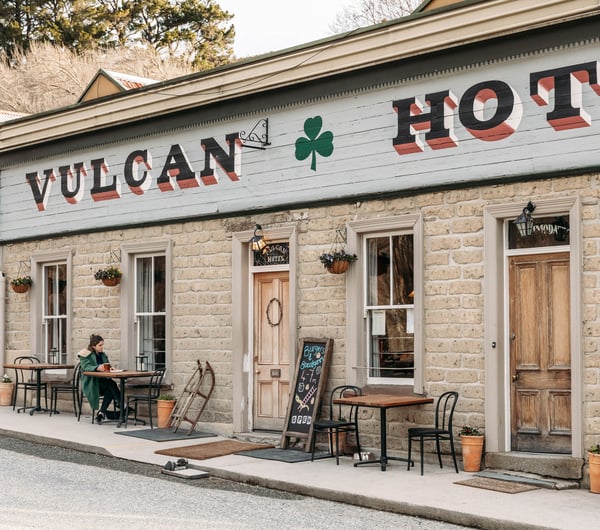 A woman sitting at a table outside Vulcan Hotel in Central Otago.