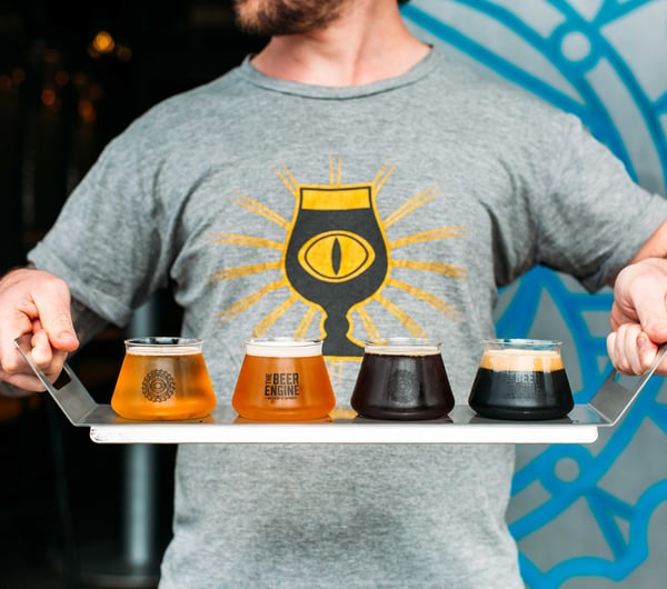 A man holding a tasting tray of beers.