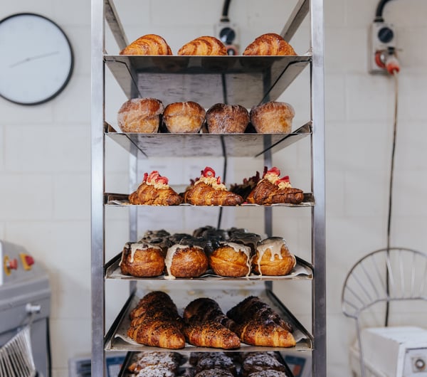 Silver trays of croissants and pastries stacked on top of each other in bakery kitchen