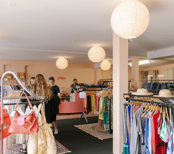 The busy and bright interior of a second hand clothing store.