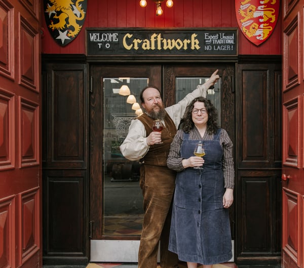 Owners of Craftwork standing outside the building with a pint in hand.
