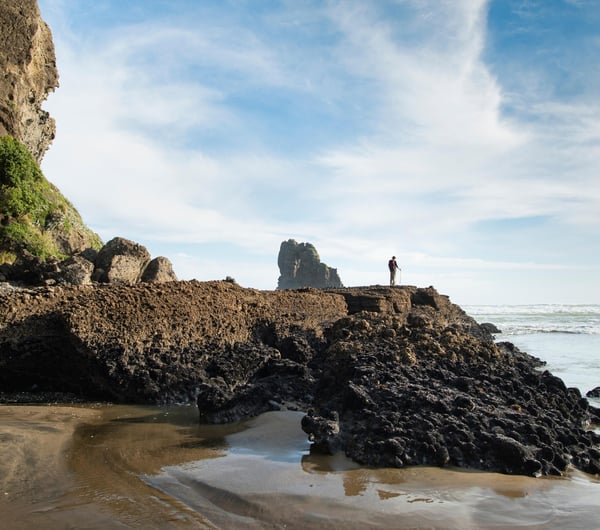 A lone man standing at Anawhata Bay.