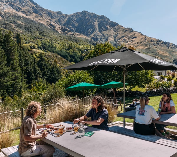 Four customers sitting at an outdoor table with nature scenery behind them.