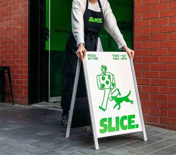 Someone putting Slice sandwich board sign outside shop