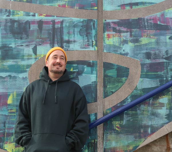 Image of male in yellow beanie infant of a painted wall.