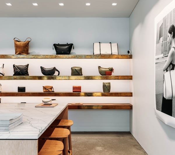 Leather bags on display on wooden floating shelves.